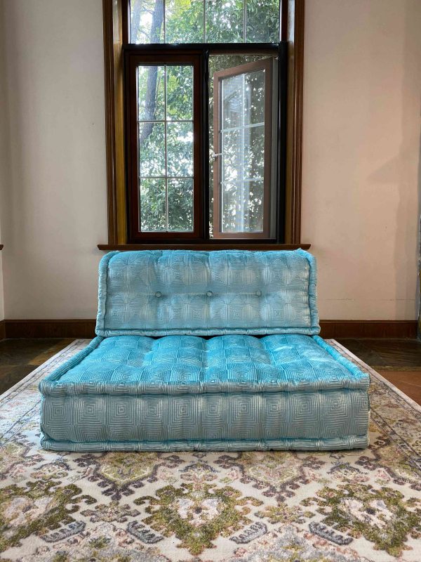 Turquoise Mah Jong modular sofa piece with tufted cushions in a bright room near a large window