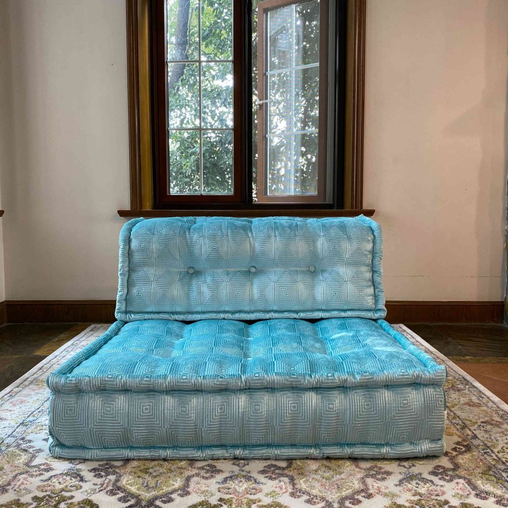 Turquoise Mah Jong modular sofa piece with tufted cushions in a bright room near a large window