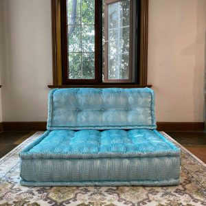 Turquoise Mah Jong modular sofa piece with tufted cushions in a bright room near a large window