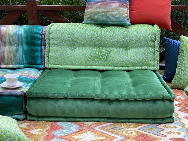 Green Mah Jong modular sofa with tufted cushions and multicolored pillows on a vibrant patterned rug