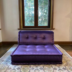 Purple Mah Jong modular sofa piece with tufted seating, placed in front of a large window