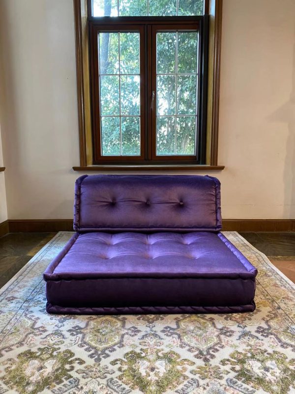 Purple Mah Jong modular sofa piece with tufted seating, placed in front of a large window