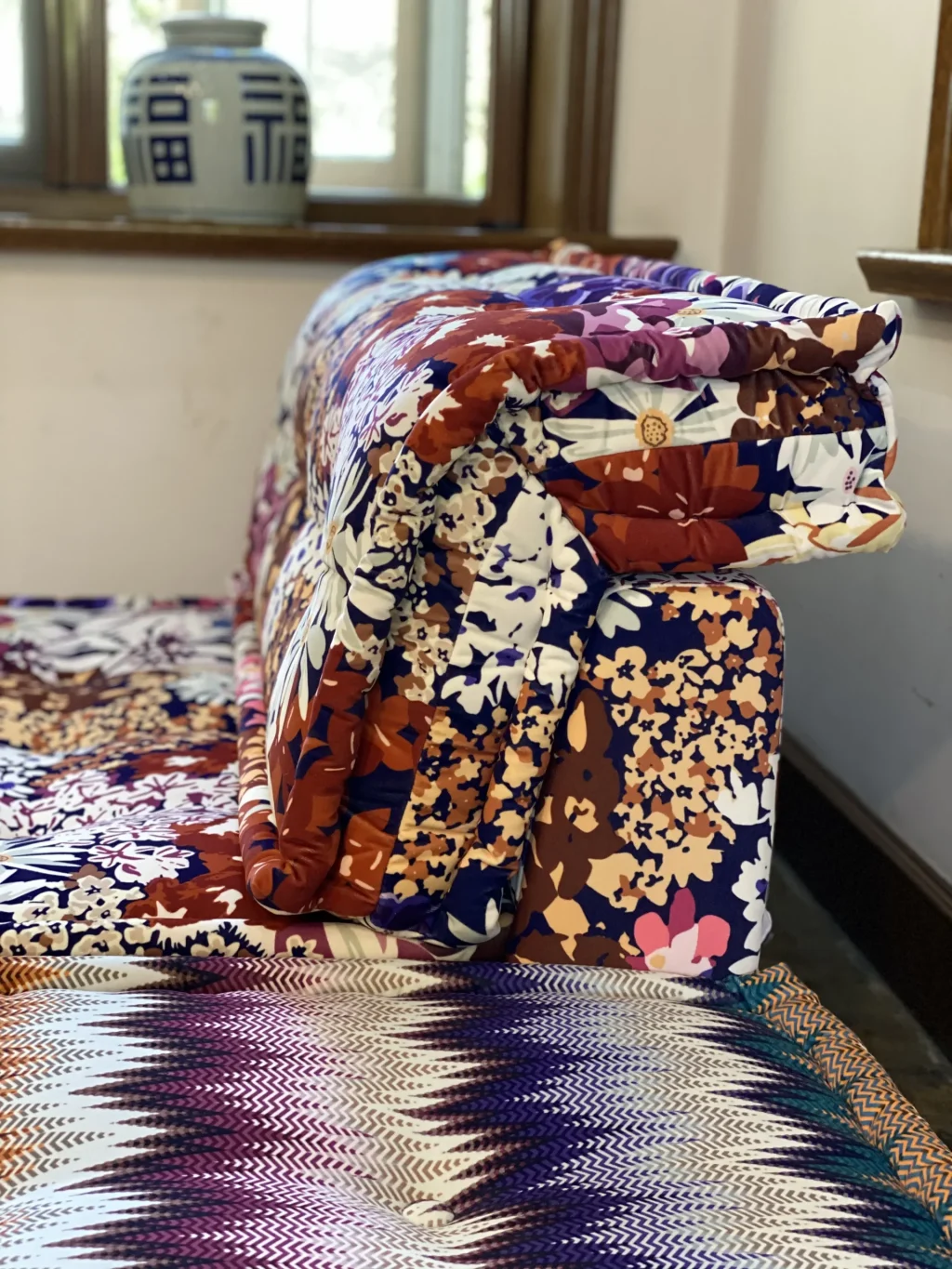 Chic floral and zigzag-patterned Mah Jong Sofa with soft, layered cushions in a cozy living space.