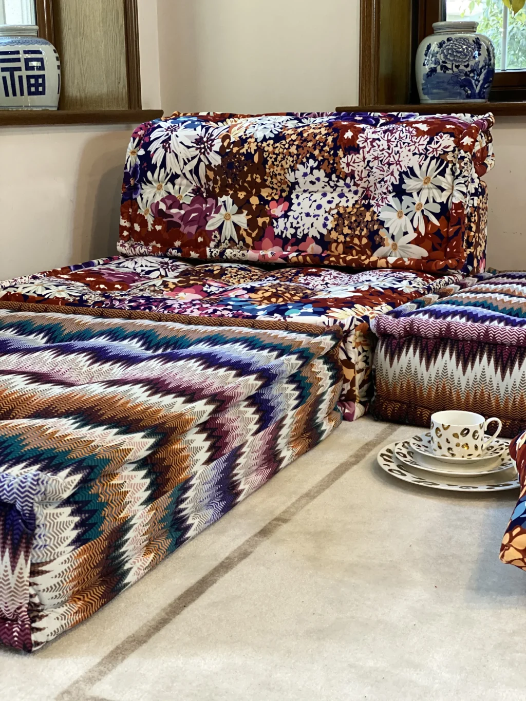 Bold zigzag and floral Mah Jong Sofa in warm tones, styled with decorative ceramics and soft lighting.