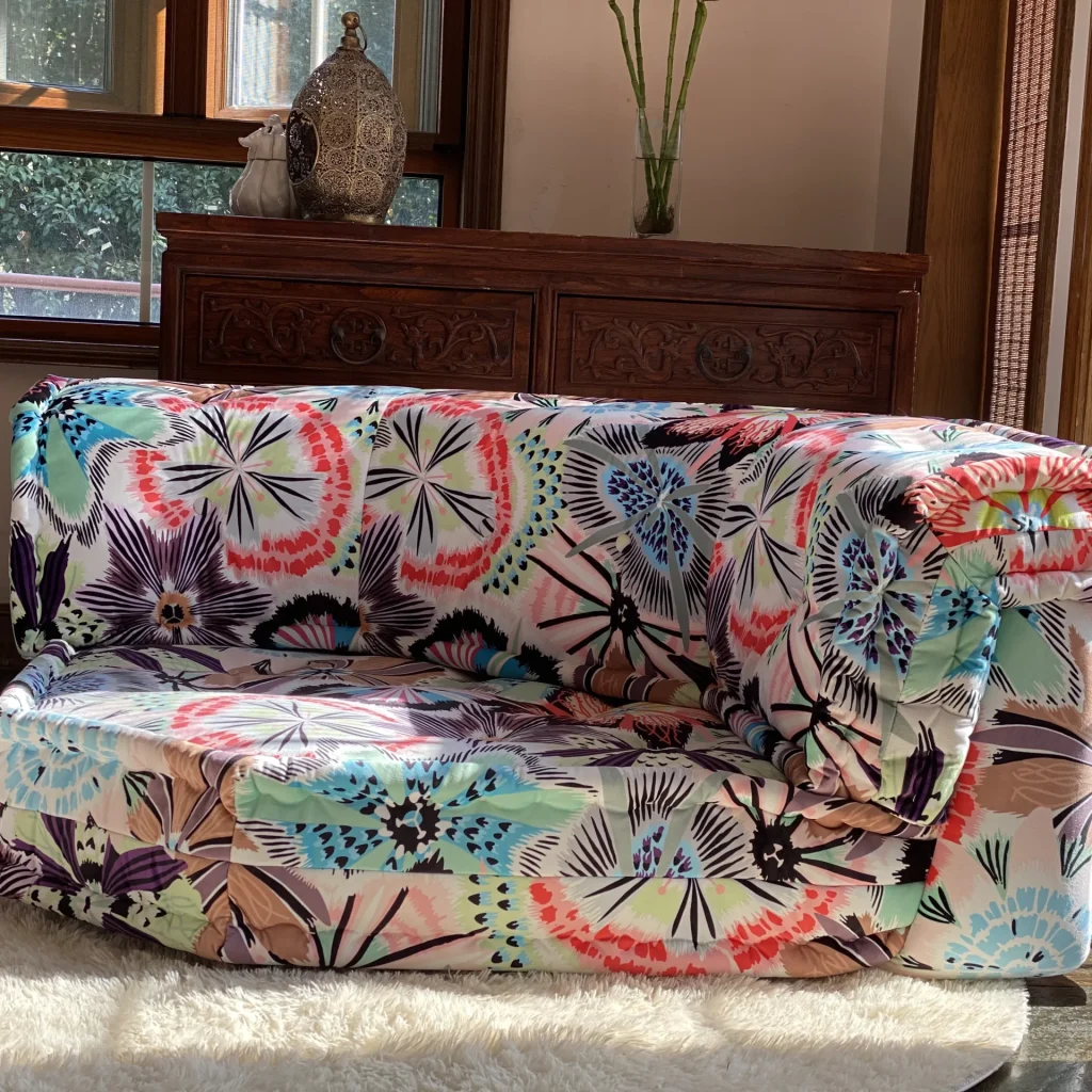 Mah Jong sofa with colorful floral fabric in a sunny interior with traditional wooden decor.