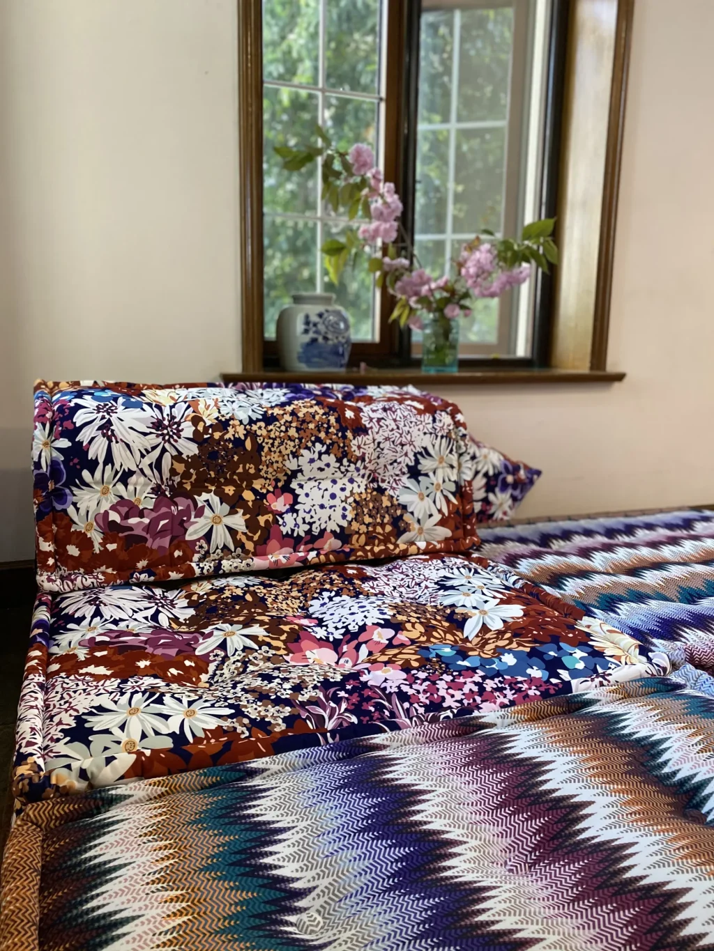 Side view of a Mah Jong Sofa with vibrant floral and zigzag patterns, paired with elegant decor.