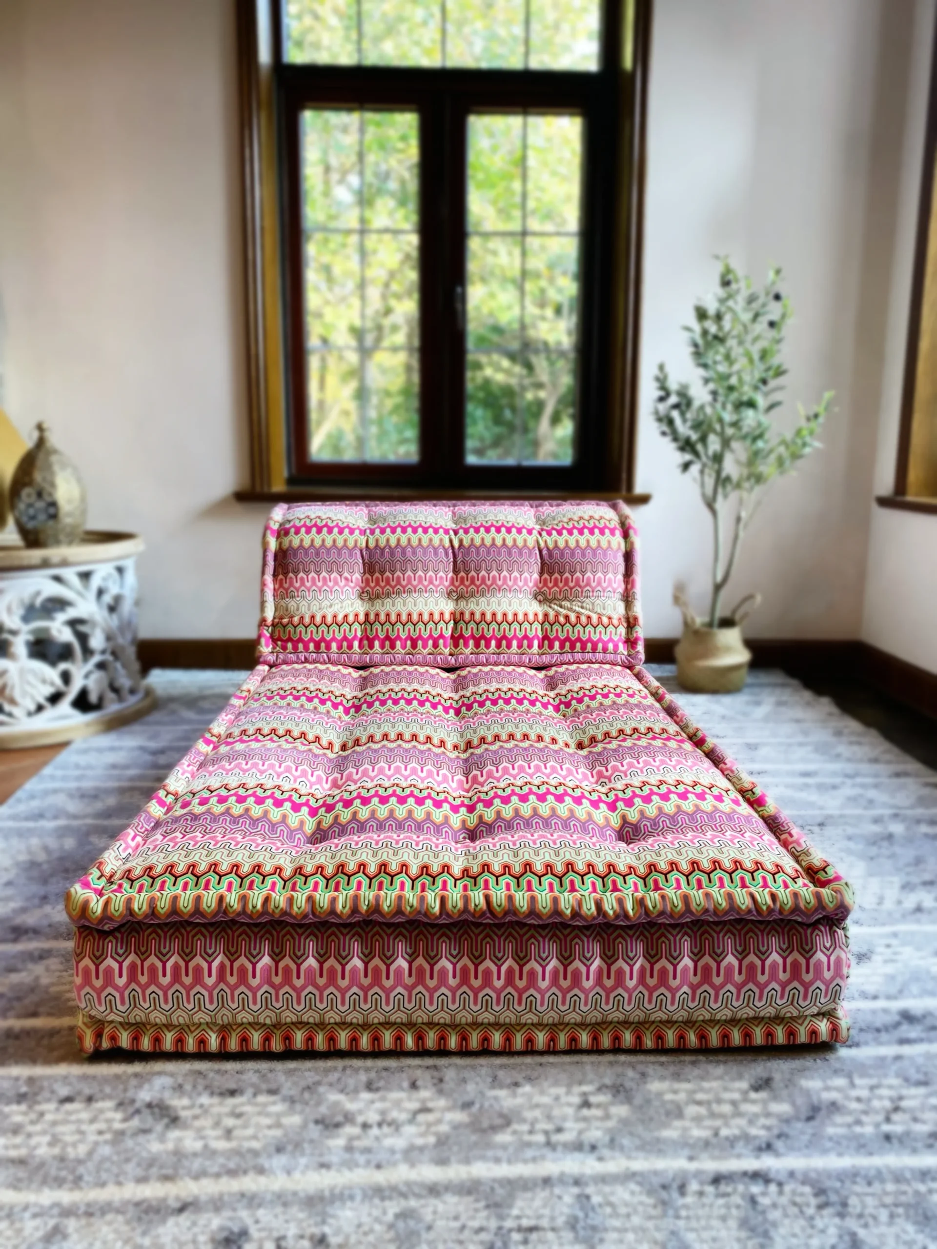 French Daybed Mah Jong sofa featuring vibrant pink and green patterned upholstery in a cozy living room setting.