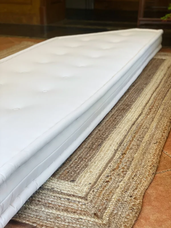 Angled perspective of the white French daybed Mah Jong sofa on a natural woven rug.