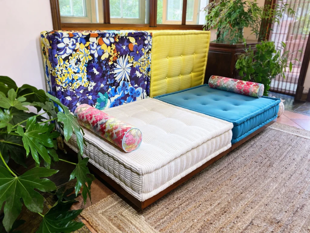 Vibrant Mah Jong Daybed Sofa featuring floral and yellow backrests, white and blue cushions, and colorful bolsters.