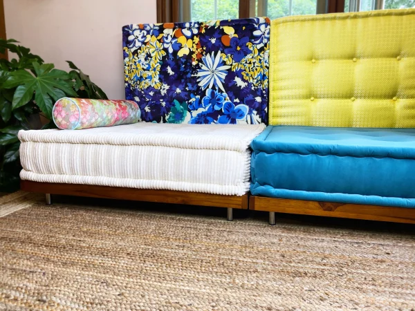 Mah Jong Sofa featuring striped white and blue cushions with floral, yellow, and blue patterned backrests.