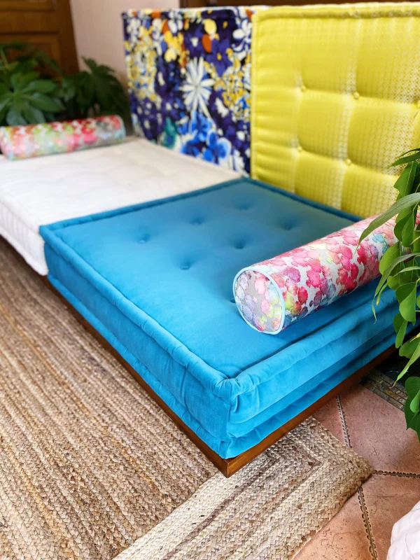 Blue Mah Jong Sofa cushion with colorful floral bolsters and striking yellow and floral-patterned backrests.