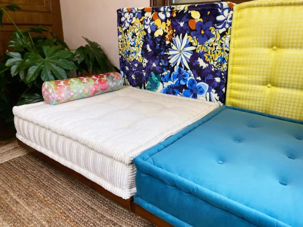 Mah Jong Daybed Sofa with vibrant floral, yellow, and blue backrests and a striped white cushion.