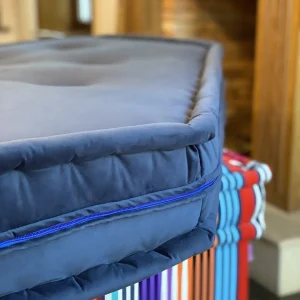 Close-up of a navy blue French Daybed Mah Jong sofa corner mat with tufted detailing and colorful striped cushions underneath.