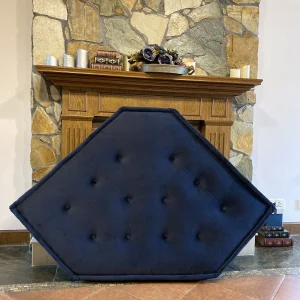 A navy blue tufted corner mat from the French Daybed Mah Jong sofa collection displayed in front of a rustic stone fireplace.