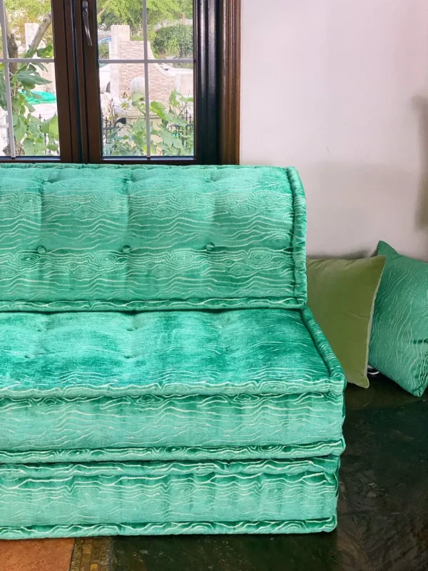 Elegant French turquoise daybed with a textured design and layered cushions in a cozy living area.