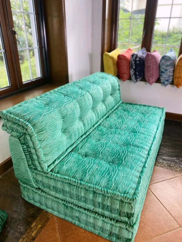 French Mah Jong daybed in turquoise with intricate fabric patterns, styled in a rustic yet modern interior