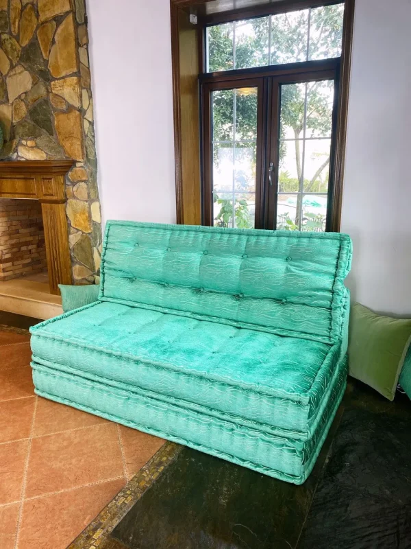 French turquoise Mah Jong daybed styled in a rustic living room setting with a fireplace and tiled flooring.