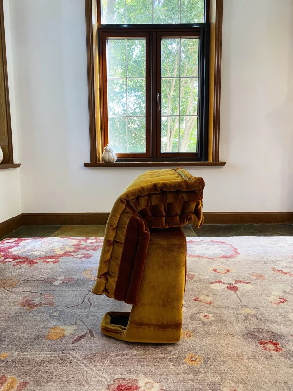 Side angle of the folded French daybed Mah Jong sofa on a floral-patterned rug.