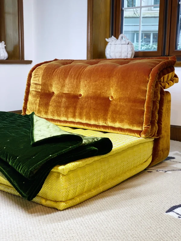 Front view of Mah Jong sofa with premium green velvet throw and yellow cushion details, placed in a modern setting.