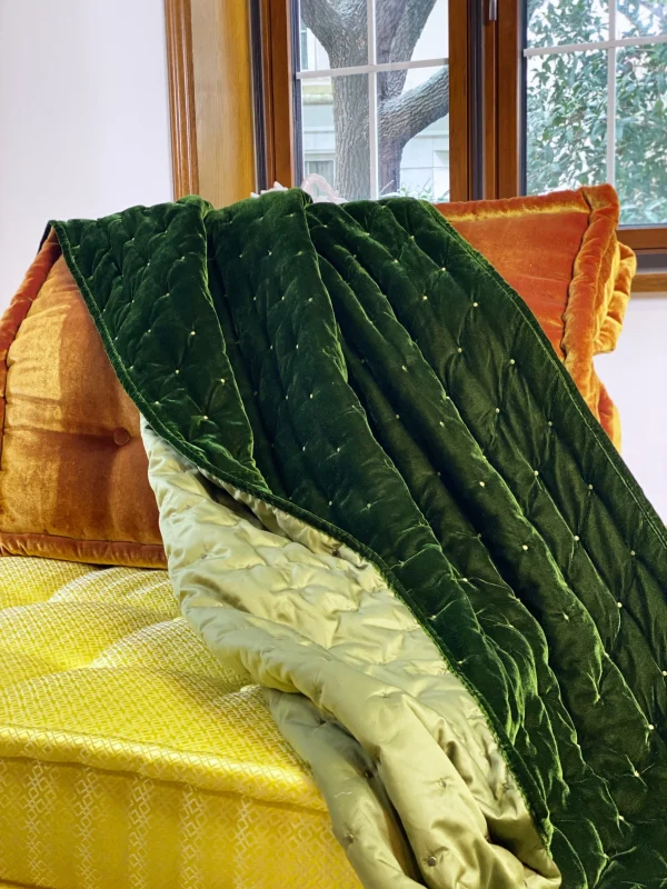 Close-up of layered green velvet throw and yellow cushion on the Mah Jong modular sofa, highlighting intricate fabric patterns.