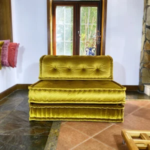 French Mah Jong daybed with golden-yellow upholstery, complemented by a classic blue vase and warm ambient lighting.