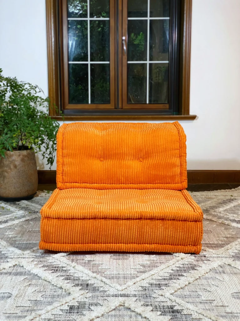 Vibrant orange French Mah Jong Daybed Sofa in a cozy living room with natural light and a textured rug.