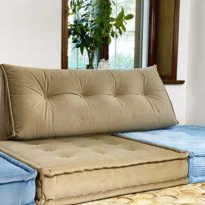 Full view of beige Mah Jong Daybed Sofa next to blue cushions, styled in a serene living room.