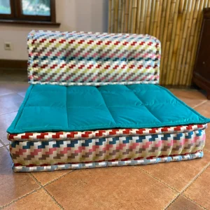 Multicolored patterned Mah Jong sofa with aqua cushion and artistic fabric design.