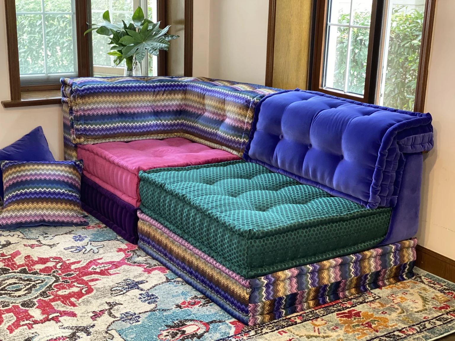 Colorful Mah Jong Sofa with zigzag patterns, pink and green cushions, and bold blue velvet upholstery in a vibrant living room.