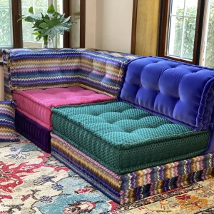 Colorful Mah Jong Sofa with zigzag patterns, pink and green cushions, and bold blue velvet upholstery in a vibrant living room.