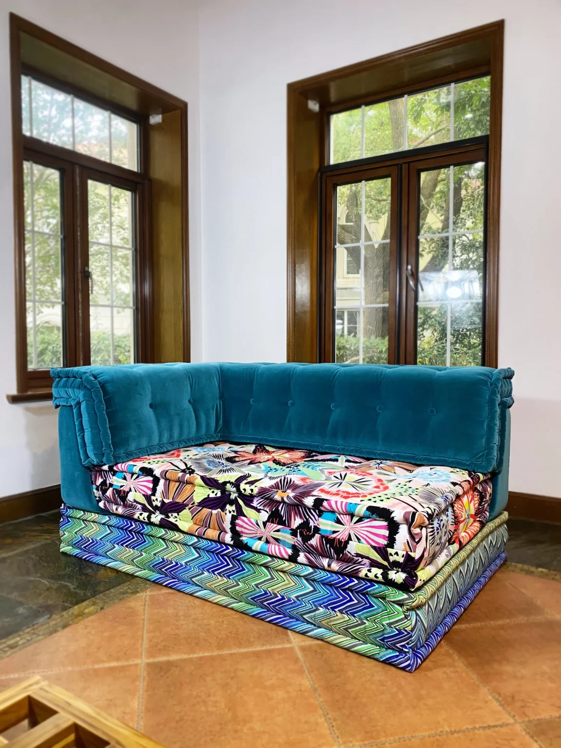 Close-up of Mah Jong daybed featuring teal velvet and detailed chevron and floral cushion designs.
