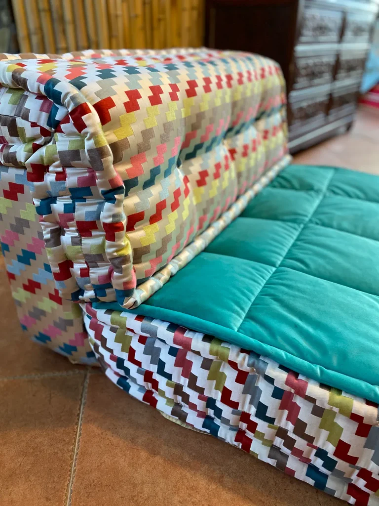 French Mah Jong sofa in aqua and gray with bamboo backdrop and wooden cabinet.