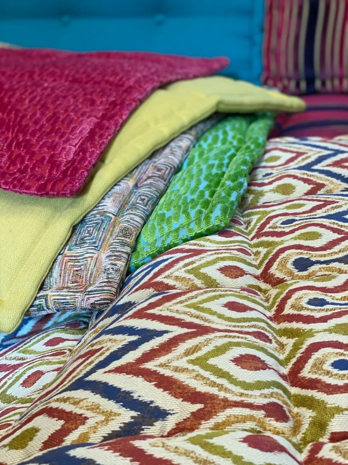 Layered fabric swatches of Mah Jong cushions in colorful patterns and textures.