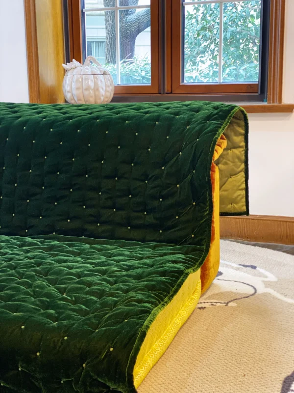 Side view of Mah Jong daybed sofa with green velvet upholstery and vibrant yellow cushion detail.