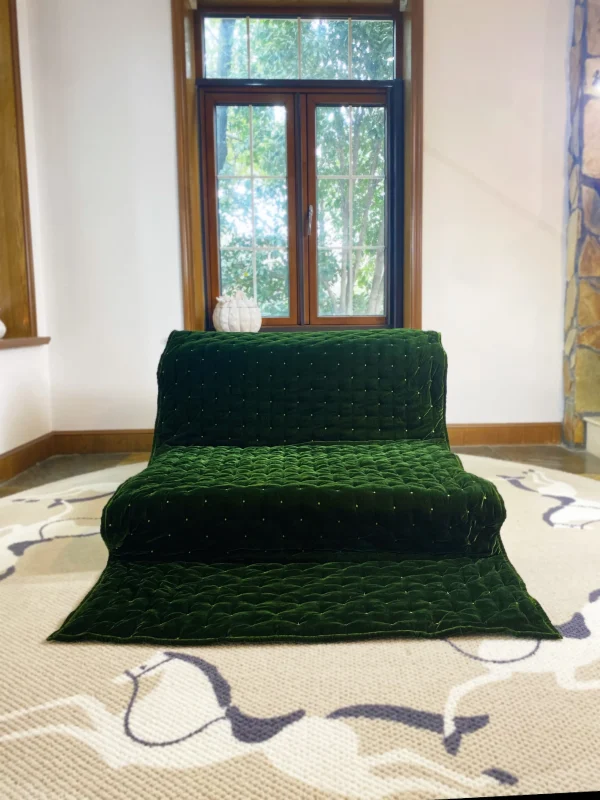 Front view of Mah Jong daybed sofa with green velvet upholstery and plush quilting, styled in a bright living room.