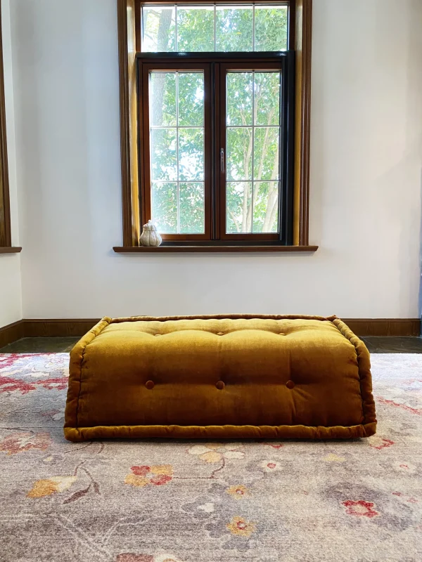 French daybed Mah Jong sofa partially folded with a matching velvet pillow on a floral rug.