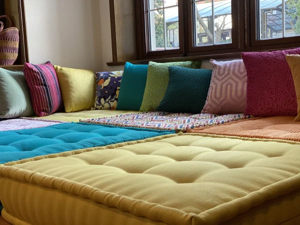 Corner view of a Mah Jong daybed with striped, geometric, and solid-colored cushions creating a cozy lounging area.