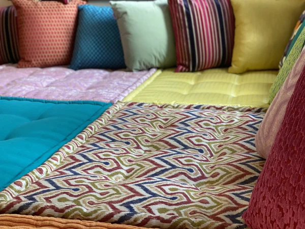 Close-up of a zigzag-patterned cushion on the Mah Jong daybed, surrounded by complementary colorful fabrics and textures.