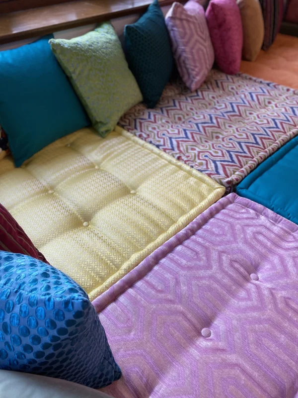 Plush Mah Jong daybed cushions arranged in bright, bold hues with intricate patterns and rich textures for a sophisticated space.