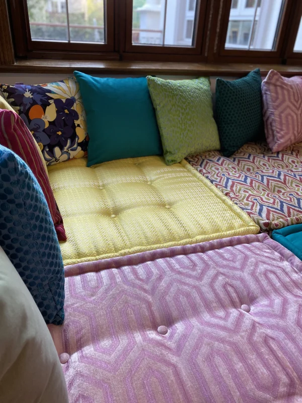 Side view of a Mah Jong daybed showcasing soft textured cushions in vibrant colors like turquoise, pink, and yellow.