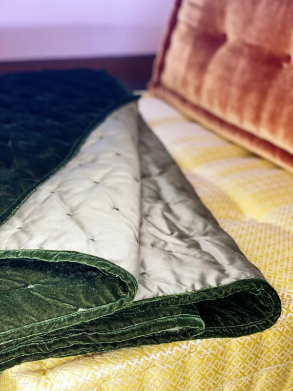 Unfolded green velvet quilt on Mah Jong daybed sofa, with contrasting yellow and orange cushions.