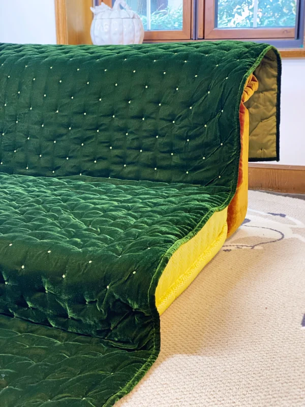 Side view of Mah Jong daybed sofa highlighting green quilted velvet upholstery and bright yellow cushions.