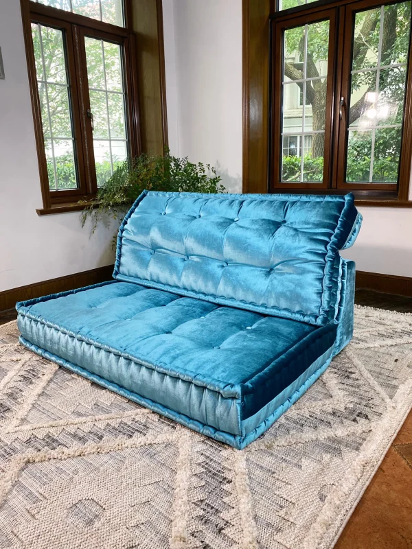 A cozy and elegant teal velvet Mah Jong daybed sofa, featured in a stylish living room with bright windows.