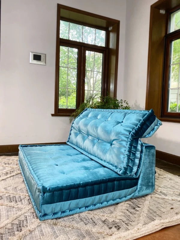 Angled front view of the teal velvet Mah Jong daybed, placed in a cozy bohemian-styled living room.