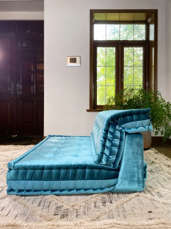 Side view of the teal velvet French Mah Jong daybed sofa, highlighting its layered cushions and soft texture in a cozy room.