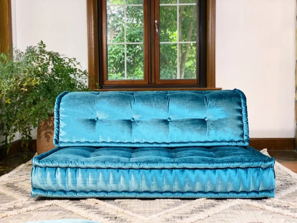 Vibrant teal velvet French Mah Jong daybed, featuring button-tufted upholstery against a natural window backdrop.