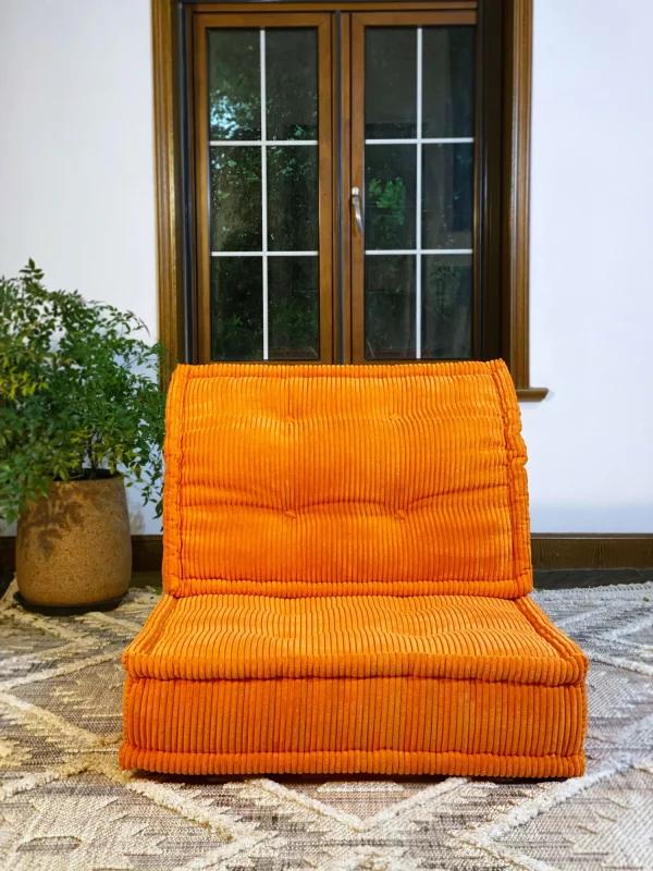 Front view of the orange Mah Jong Sofa with tufted details and ribbed texture, placed in a bright room.