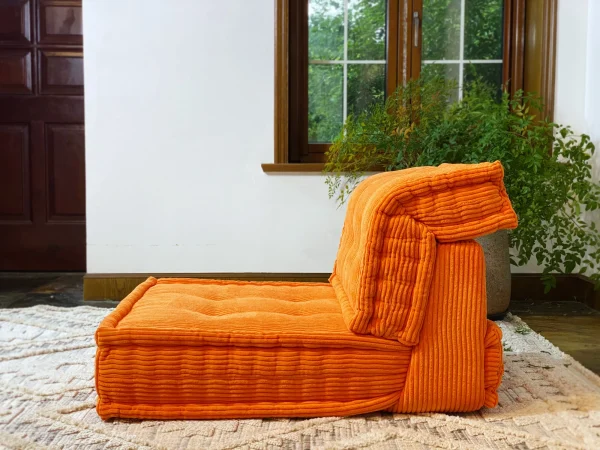 Side view of the orange Mah Jong Daybed Sofa showing its plush cushioning and ribbed texture.