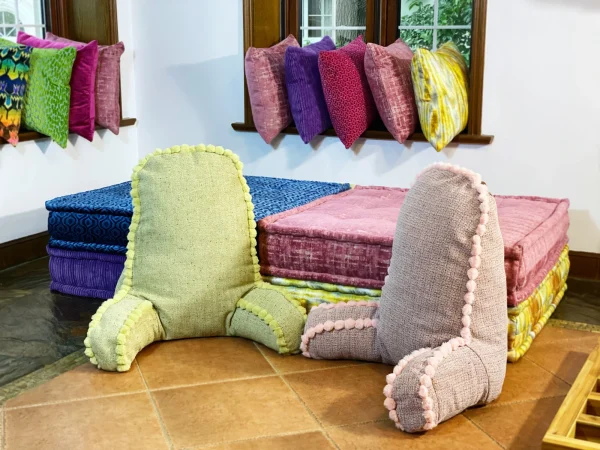 Green pom-pom backrest cushion placed against a colorful backdrop of Mah Jong sofa cushions.