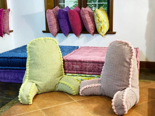 Side view of pink and green pom-pom backrest cushions on a vibrant Mah Jong daybed.